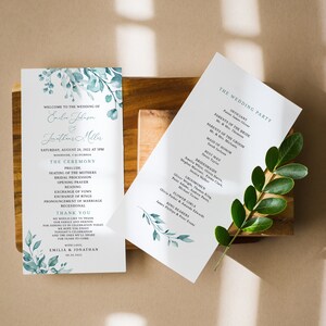 May include: Wedding ceremony program with a watercolor floral design in shades of blue and green. The program lists the order of events for the ceremony, including the officiant, parents of the bride and groom, maid of honor, best man, bridesmaids, groomsmen, flower girls, and ring bearers.