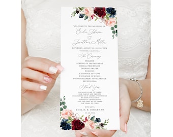 May include: Wedding ceremony program with a floral design featuring burgundy, pink, and blue flowers. The program lists the order of events for the wedding of Emelie and Jonathan on August 20, 2022.