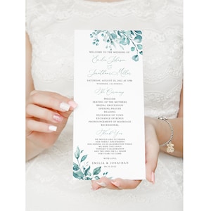 May include: A wedding ceremony program with a watercolor floral design in shades of blue and green. The program lists the order of events for the wedding of Emilie Johnson and Jonathan Miller, taking place on August 20, 2022, in Woodside, California.