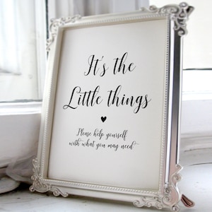 May include: A framed sign with the text "It's the Little things" in elegant script, with a small heart symbol. The frame is silver with ornate detailing. The bottom of the sign reads "Please help yourself with what you may need."