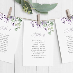 May include: Three white cards with floral designs and the text "Table 1", "Table 2", and "Table 3" with a list of names under each table number.