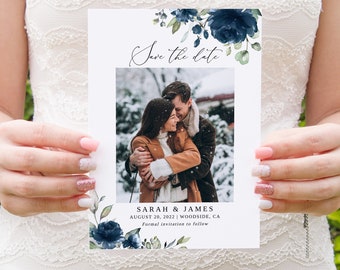 May include: Save the date card with a photo of a couple in a snowy setting. The card features a blue and green floral design with the text "Save the date" and the couple's names, "Sarah & James", the date "August 20, 2022", the location "Woodside, CA", and the phrase "Formal invitation to follow".