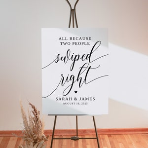May include: White wedding sign with black text that reads "All because two people swiped right. Sarah & James August 16, 2025".