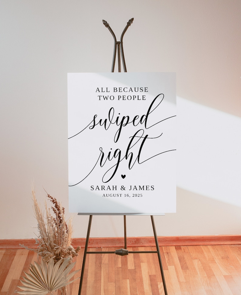 May include: White wedding sign with black text that reads "All because two people swiped right. Sarah & James August 16, 2025".