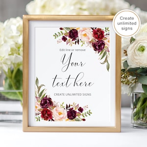Peut inclure: Un panneau encadr&eacute; avec une bordure dor&eacute;e, orn&eacute; de compositions florales bordeaux, blanches et vertes. Le panneau indique "Your text here" avec le texte "Create unlimited signs" en dessous. Le panneau est affich&eacute; pr&egrave;s d'un bouquet de fleurs blanches.
