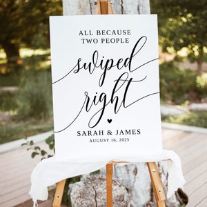 May include: White wedding sign with black text that reads "All because two people swiped right. Sarah & James August 16, 2025".
