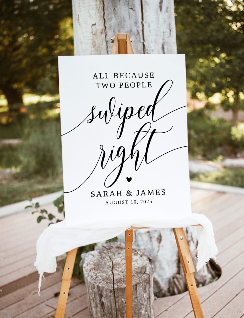 May include: White wedding sign with black text that reads "All because two people swiped right. Sarah & James August 16, 2025".