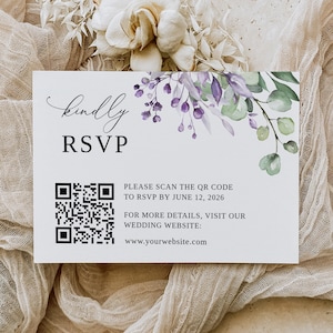 May include: A white card with a floral design in shades of purple and green. The text "kindly RSVP" is printed in black at the top of the card. A QR code is printed in black in the center of the card. The text "PLEASE SCAN THE QR CODE TO RSVP BY JUNE 12, 2026" is printed in black below the QR code. The text "FOR MORE DETAILS, VISIT OUR WEDDING WEBSITE: www.yourwebsite.com" is printed in black below the QR code.