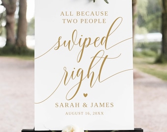 Puede incluir: Un letrero de boda blanco con texto de caligrafía dorada que dice: "Todo porque dos personas deslizaron a la derecha". El letrero incluye los nombres "Sarah & James" y la fecha "16 de agosto de 20XX". El letrero está sobre un caballete negro, decorado con flores blancas.