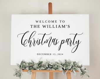 May include: White sign with black text that reads "Welcome to The William's Christmas Party December 12, 2024". The sign is on an easel with greenery.
