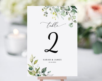 May include: White table number card with green watercolor leaves and the text "table 2" and "SARAH & JAMES 10.14.2022".