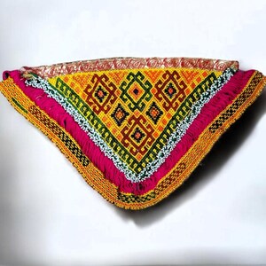 Op de afbeelding: Een driehoekig kussen met kralen met een geometrisch patroon in tinten geel, groen, rood en zwart. Het kussen heeft een roze franje rand en een gele kralenbies.