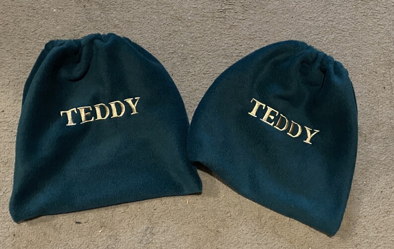 Peut inclure: Deux sacs &agrave; cordon bleu sarcelle avec le mot "TEDDY" brod&eacute; en or sur le devant.
