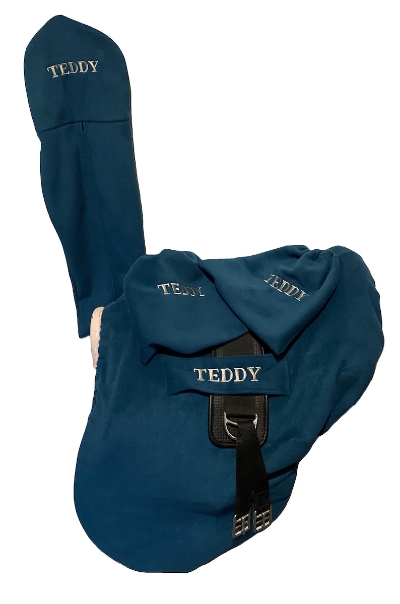 Peut inclure: Une housse de selle bleu sarcelle avec le nom "Teddy" brod&eacute; dessus. La housse a un rabat qui recouvre les &eacute;triers de la selle.