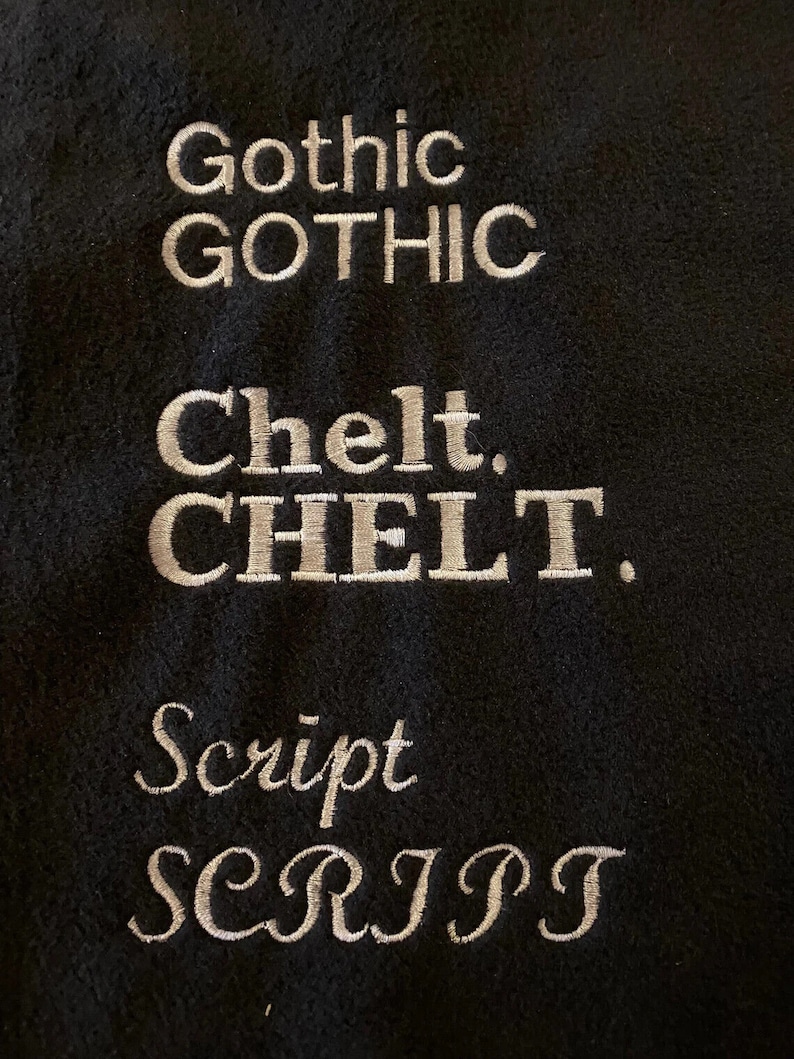 Peut inclure: Un &eacute;chantillon de tissu noir avec trois styles de police diff&eacute;rents brod&eacute;s en fil blanc. La premi&egrave;re police est &eacute;tiquet&eacute;e "Gothic", la deuxi&egrave;me est &eacute;tiquet&eacute;e "Chelt" et la troisi&egrave;me est &eacute;tiquet&eacute;e "Script".
