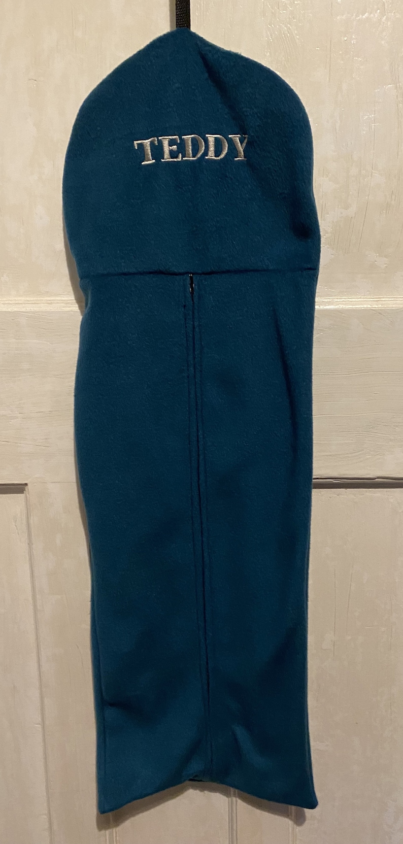 Peut inclure: Un sac de couchage en polaire bleu sarcelle avec une fermeture &eacute;clair et le nom "TEDDY" brod&eacute; sur le dessus.