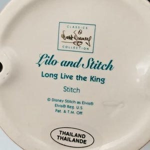 K&ouml;nnte beinhalten: Keramik-Figurenfu&szlig; mit dem Text "Lilo and Stitch" und "Long Live the King". Der Sockel tr&auml;gt auch den Text "Stitch" und "Disney Stitch as Elvis". Die Figur stammt aus der "Classics Collection" und wurde in Thailand hergestellt.