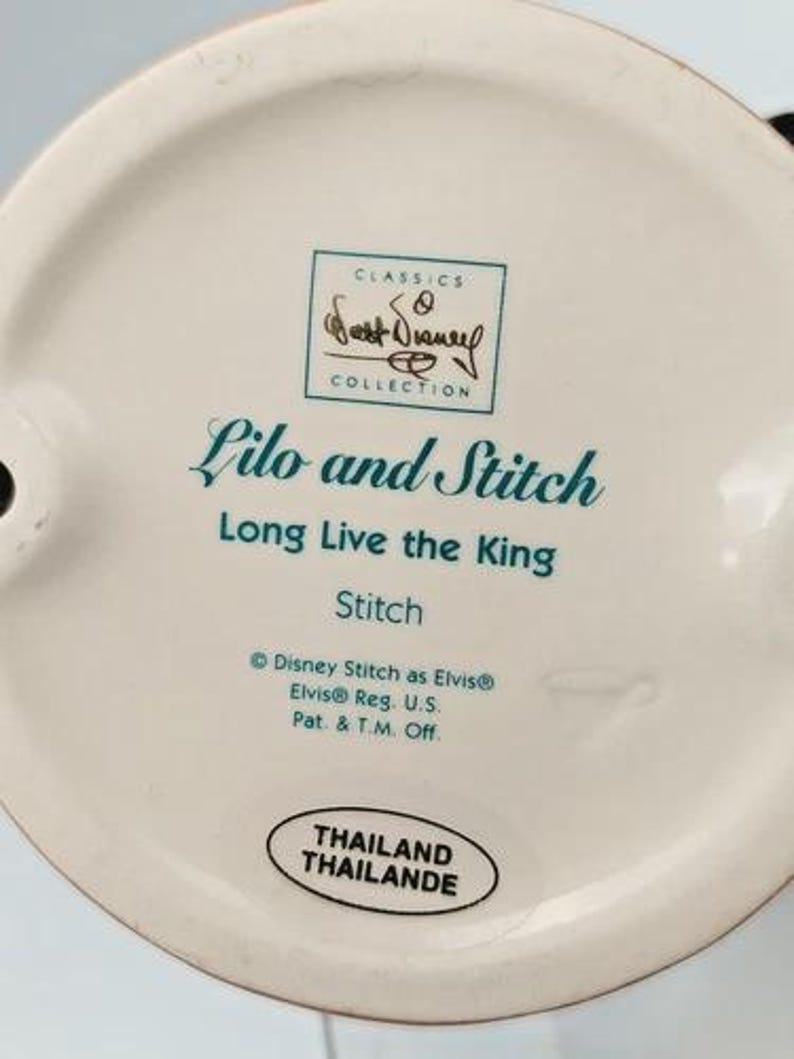 K&ouml;nnte beinhalten: Keramik-Figurenfu&szlig; mit dem Text "Lilo and Stitch" und "Long Live the King". Der Sockel tr&auml;gt auch den Text "Stitch" und "Disney Stitch as Elvis". Die Figur stammt aus der "Classics Collection" und wurde in Thailand hergestellt.