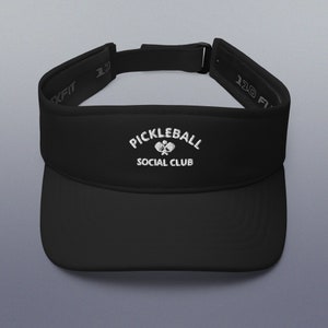 Puede incluir: Visera negra con un logotipo bordado en blanco que dice "Pickleball Social Club" con un gráfico de raqueta de pickleball.
