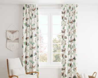 May include: White curtain panels with a repeating pattern of woodland animals and green foliage. The curtains are hanging in front of a window, with a chair and basket in the foreground. The design includes deer, foxes, and owls.