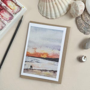 Tarjeta de felicitación de acuarela pintada a mano con un atardecer en la playa de South Milton Sands