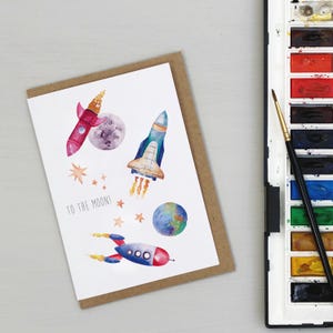 Tarjeta de cumpleaños con cohetes en el espacio exterior