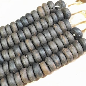 May include: A strand of dark brown wooden beads, each bead is round and slightly textured. The beads are arranged in a staggered pattern, creating a visual rhythm.