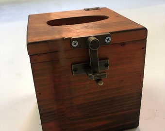 May include: A wooden tissue box cover with a hinged lid and a brass latch. The box is stained a dark reddish brown color.