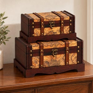 May include: Two rectangular wooden storage chests stacked on top of each other. Each chest features a dark brown frame, a vintage map print on the lid and front panel, brass-colored metal latches, and decorative brass studs along the edges.