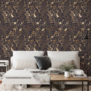 May include: A white bed with a white duvet and a brown wooden coffee table in front of it. The wall behind the bed is covered in a dark blue wallpaper with a gold floral pattern.