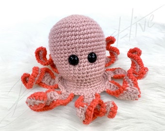 May include: A crocheted octopus plush toy with a pink body and orange tentacles. The octopus has black button eyes.