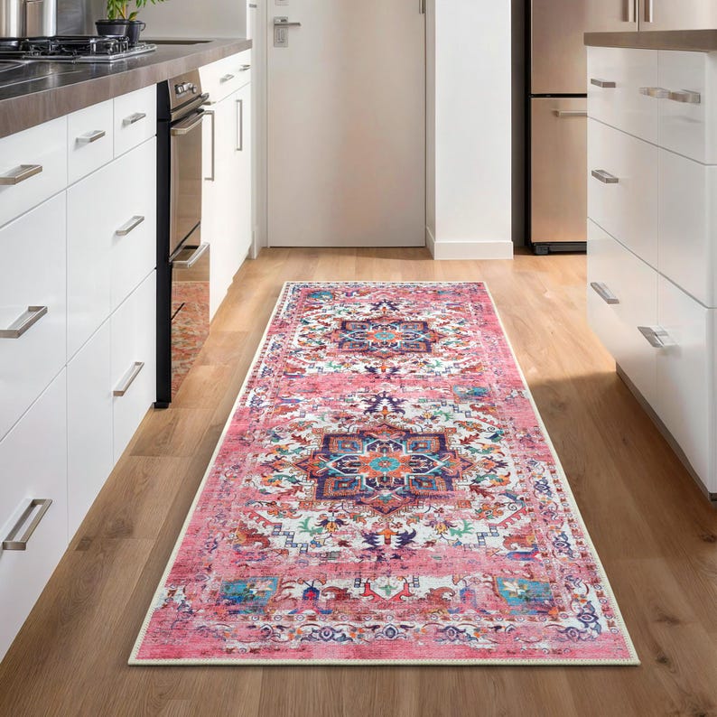 Puede incluir: Una alfombra rectangular con estampado rosa y blanco con un dise&ntilde;o de medall&oacute;n central. La alfombra presenta un aspecto envejecido y vintage con una mezcla de elementos florales y geom&eacute;tricos. La alfombra est&aacute; colocada en una cocina.