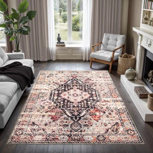 May include: A large, rectangular area rug with an ornate, traditional design. The rug features a central black medallion with intricate patterns, surrounded by a beige and red border. The rug is placed on a dark hardwood floor in a living room setting.