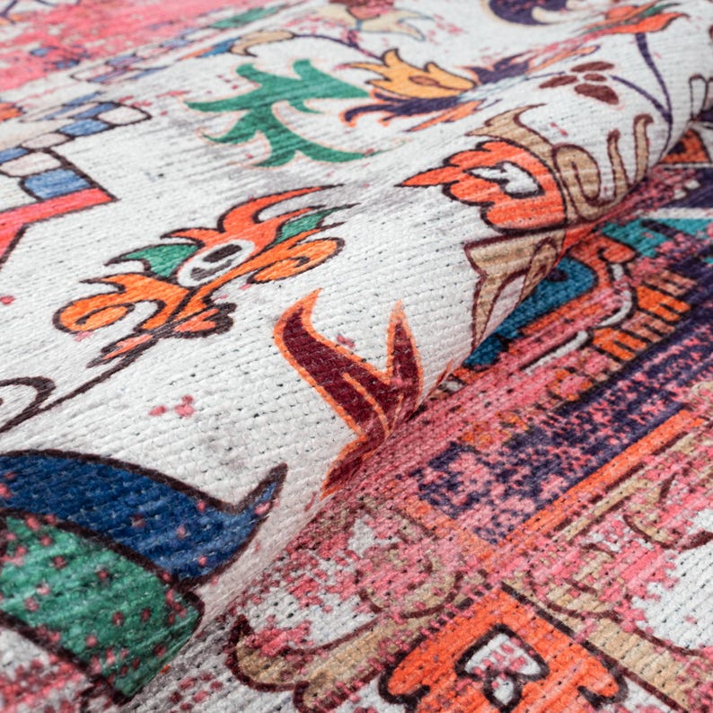 Puede incluir: Primer plano de una alfombra enrollada con un patr&oacute;n detallado y colorido. El dise&ntilde;o presenta elementos florales y geom&eacute;tricos en tonos naranja, rosa, azul, verde y morado sobre un fondo blanco. La alfombra tiene una apariencia texturizada.