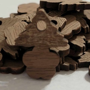 May include: A pile of brown wooden ornaments shaped like Christmas trees. The ornaments have a hole in the top for hanging.