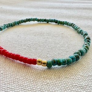 May include: A turquoise and red beaded bracelet with gold accents. The bracelet is made of small, round beads and is strung on a thin cord.