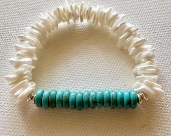 May include: A handmade bracelet featuring white shell chips and turquoise-colored beads. The bracelet is strung on a flexible cord and has silver-colored metal accents. The design is simple and elegant, suitable for everyday wear.