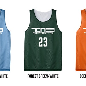 May include: Three reversible basketball jerseys in Carolina Blue/White, Forest Green/White, and Deep Orange/White. Each jersey features the text "TONE3 SPORTS" and the number "23" in white. The jerseys are displayed against a white background.