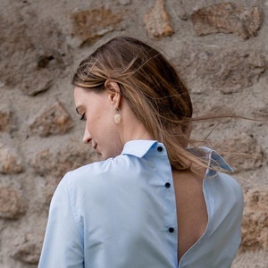 Collegiate-style pure cotton women's shirt, buttoning on the back.