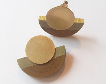 May include: A pair of gold and wood earrings. Each earring features a round gold disc on top of a half-circle of wood.