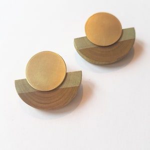 Puede incluir: Un par de pendientes de oro y madera. Cada pendiente tiene un disco redondo de oro sobre un semic&iacute;rculo de madera.