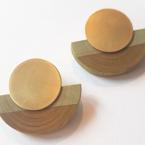 Puede incluir: Un par de pendientes de oro y madera. Cada pendiente tiene un disco redondo de oro sobre un semic&iacute;rculo de madera.