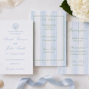 May include: A wedding invitation suite featuring a white card with blue text and a shell icon, alongside two cards with light blue vertical stripes. The text includes names Sarah Gwinn and John Smith, date 21st August 2027, and venue details.