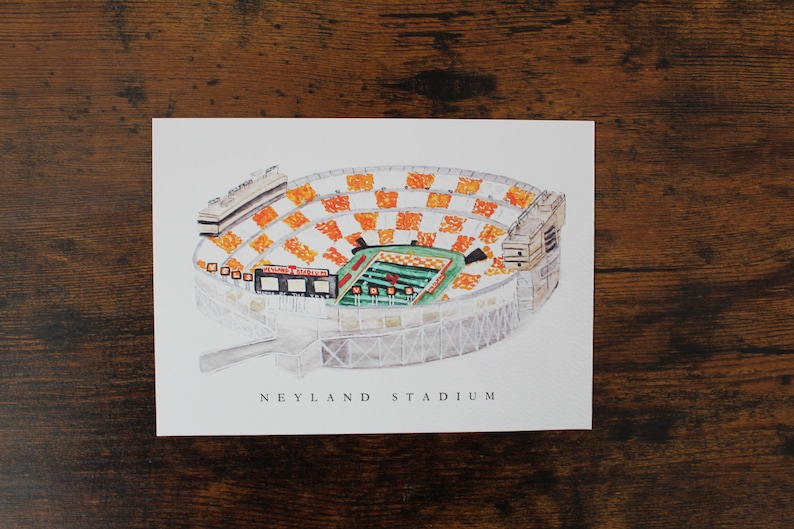 Pu&ograve; includere: Un'illustrazione ad acquerello del Neyland Stadium, casa della squadra di football americano dei Volunteers dell'Universit&agrave; del Tennessee. Lo stadio &egrave; rappresentato in una vista aerea, mostrando i sedili arancioni e bianchi e il campo verde.