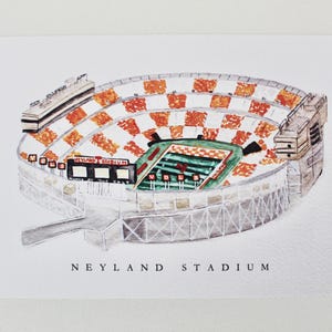 Pu&ograve; includere: Un'illustrazione ad acquerello del Neyland Stadium, casa della squadra di football americano dei Volunteers dell'Universit&agrave; del Tennessee. Lo stadio &egrave; raffigurato in arancione e bianco, con un campo verde e un tabellone segnapunti che recita "Neyland Stadium".