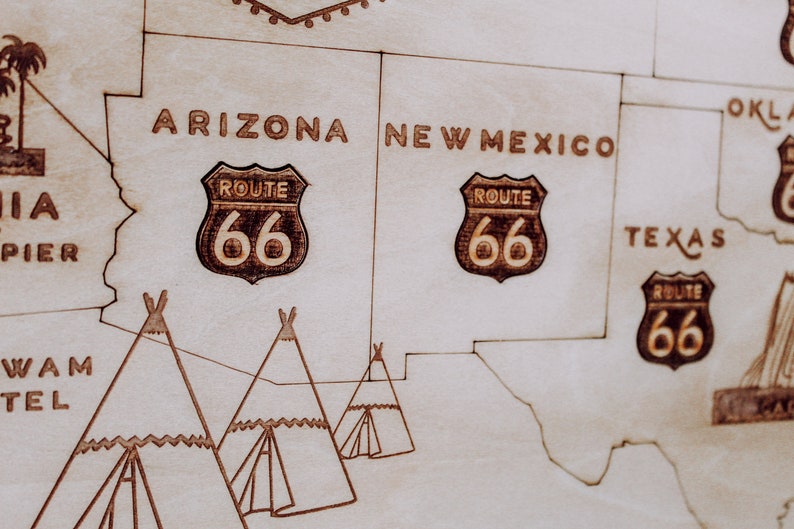 Puede incluir: Un mapa de madera de los Estados Unidos con la Ruta 66 resaltada en marr&oacute;n. El mapa muestra los estados de Arizona, Nuevo M&eacute;xico, Texas y Oklahoma. Las palabras "Ruta 66" est&aacute;n escritas en marr&oacute;n en el mapa. Tambi&eacute;n hay tres tipis dibujados en el mapa.