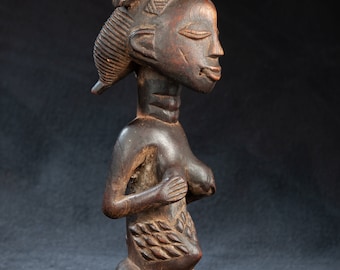 May include: A dark wood sculpture of a kneeling woman with a detailed hairstyle. The sculpture is carved with intricate details and has a traditional African style.