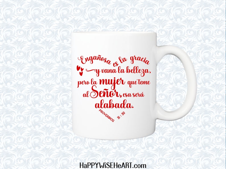May include: White ceramic mug with a curved handle. The mug features red script that reads "Enga&ntilde;osa es la gracia y vana la belleza, pero la mujer que teme al Se&ntilde;or, esa ser&aacute; alabada. PROVERBIOS 31:30". The website HAPPYWISEHEART.com is at the bottom.
