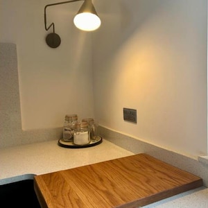 Large wooden sink cover chopping board made of natural oak grain, styled in a modern kitchen setting.