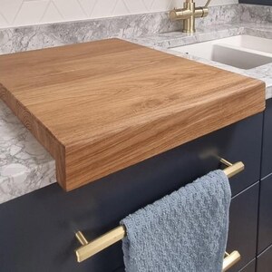 The Stability Feature (Close-up): Detailed view of the 90-degree front-edge lip on a handcrafted oak carving board, demonstrating how it prevents movement during food preparation on smooth surfaces like granite or quartz.